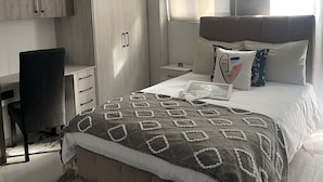 Ett modernt sovrum med en säng, ett skrivbord och en garderob.