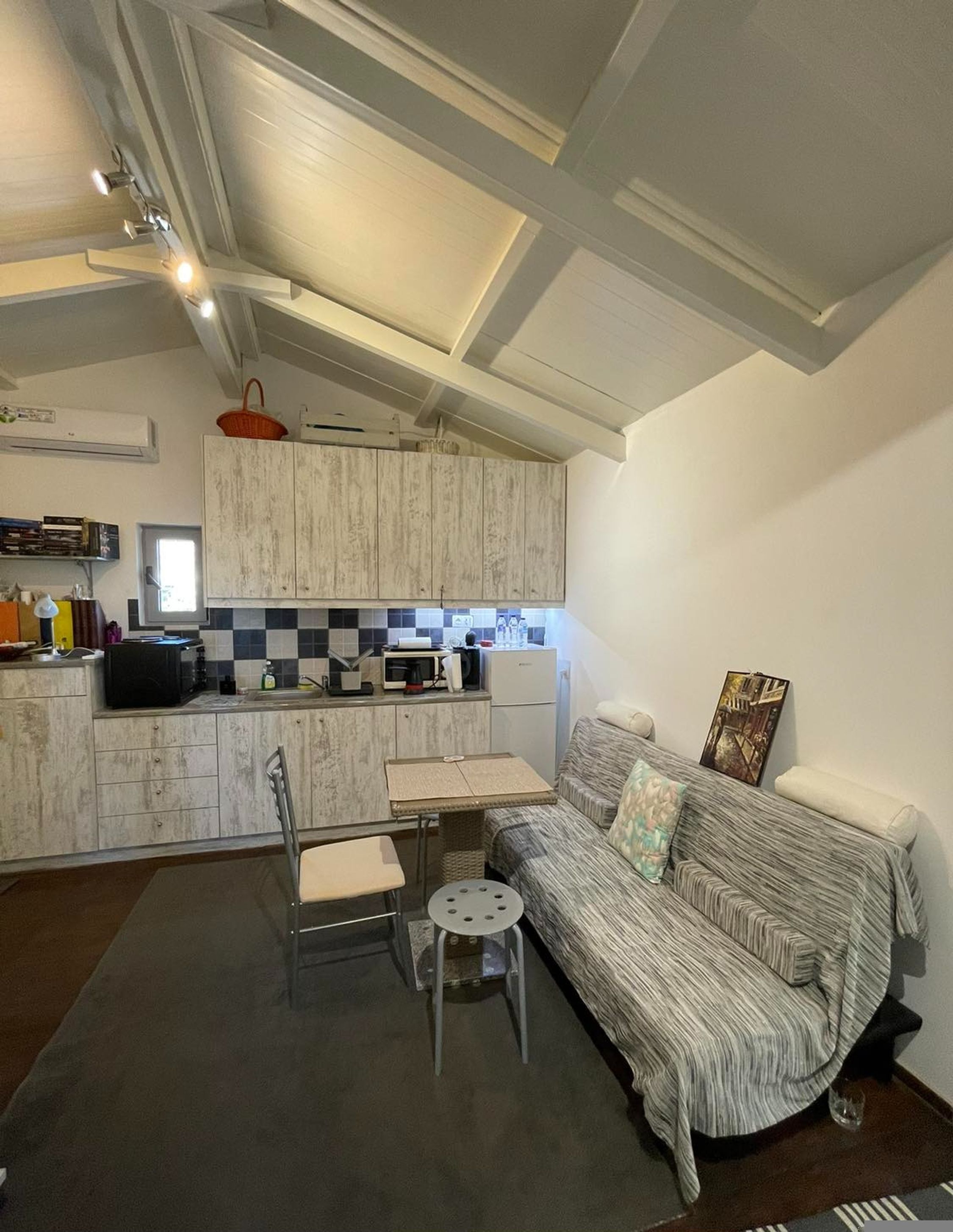 A compact living space with a kitchenette, a sofa, and a small dining table.