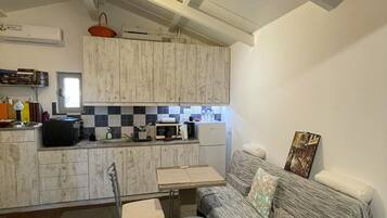 A compact living space with a kitchenette, a sofa, and a small dining table.