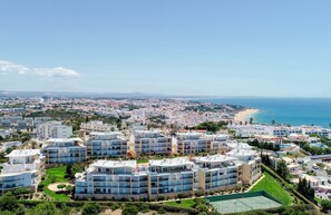 Ein Küstenwohngebiet mit modernen Mehrfamilienhäusern, einem Strand und blauem Himmel.