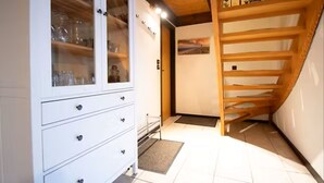 A room with a white cabinet with glass doors, a wooden staircase, and a tiled floor. - Family-friendly vacation home in Burhave - 500 m to the beach, WLAN, garden (Burhave)