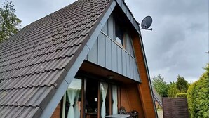 A two-story house with a sloped roof, large windows, and a satellite dish. - Family-friendly vacation home in Burhave - 500 m to the beach, WLAN, garden (Burhave)
