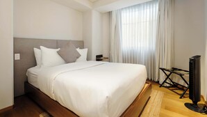 Une chambre d’hôtel avec un grand lit, un téléviseur à écran plat et une fenêtre avec des rideaux.
