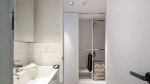 Une salle de bain moderne avec une baignoire blanche, un miroir et une douche à l’italienne dotée d’un porte-serviettes suspendu.