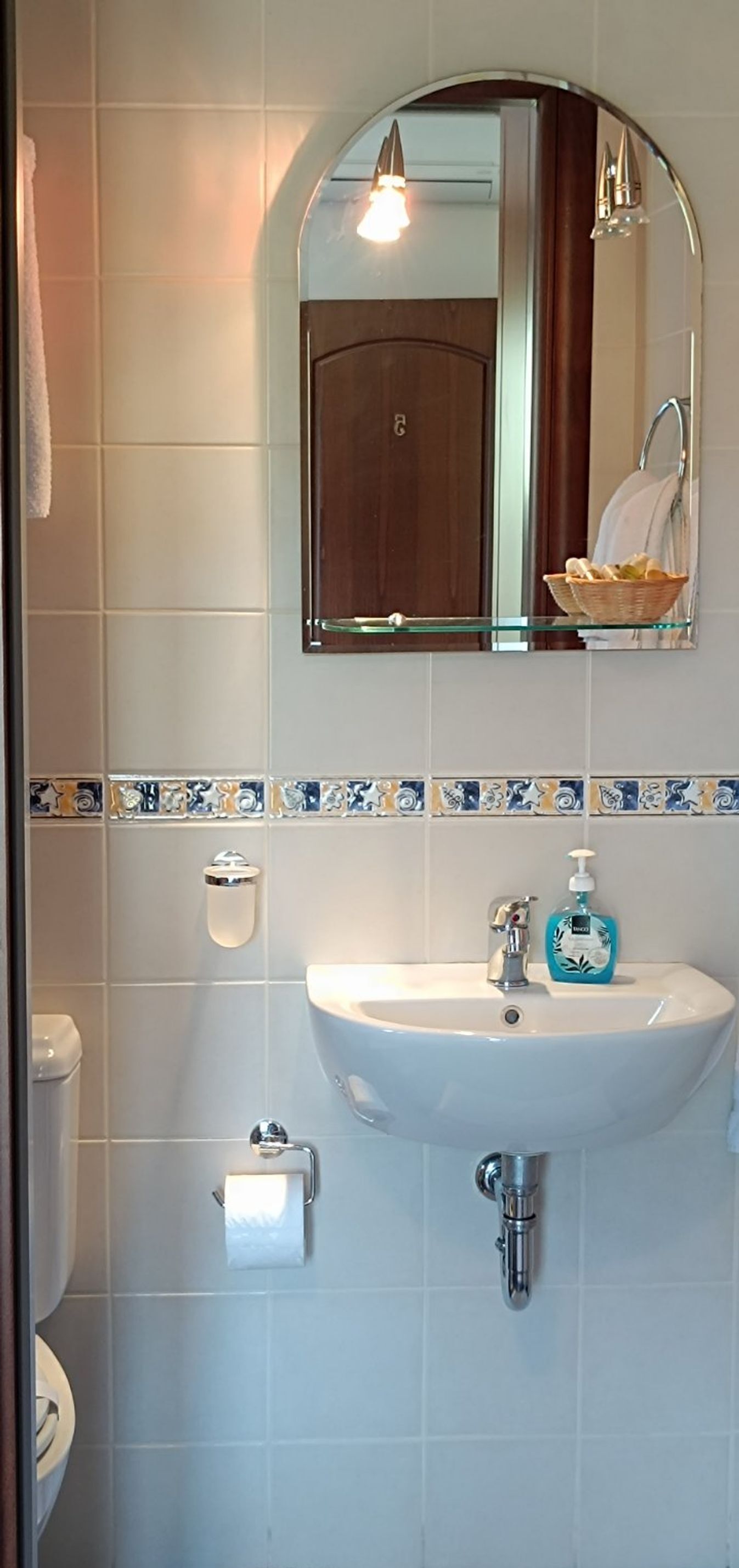 Une salle de bain avec un lavabo blanc, un miroir et des toilettes.