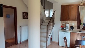 Eine moderne Küche mit eingebautem Geschirrspüler, eine Essecke mit Tisch und Stühlen, eine Treppe, die zu einer oberen Etage führt, und ein Flachbildfernseher an der Wand.