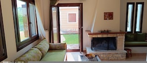 Una sala de estar con sofá, chimenea y vistas al exterior.