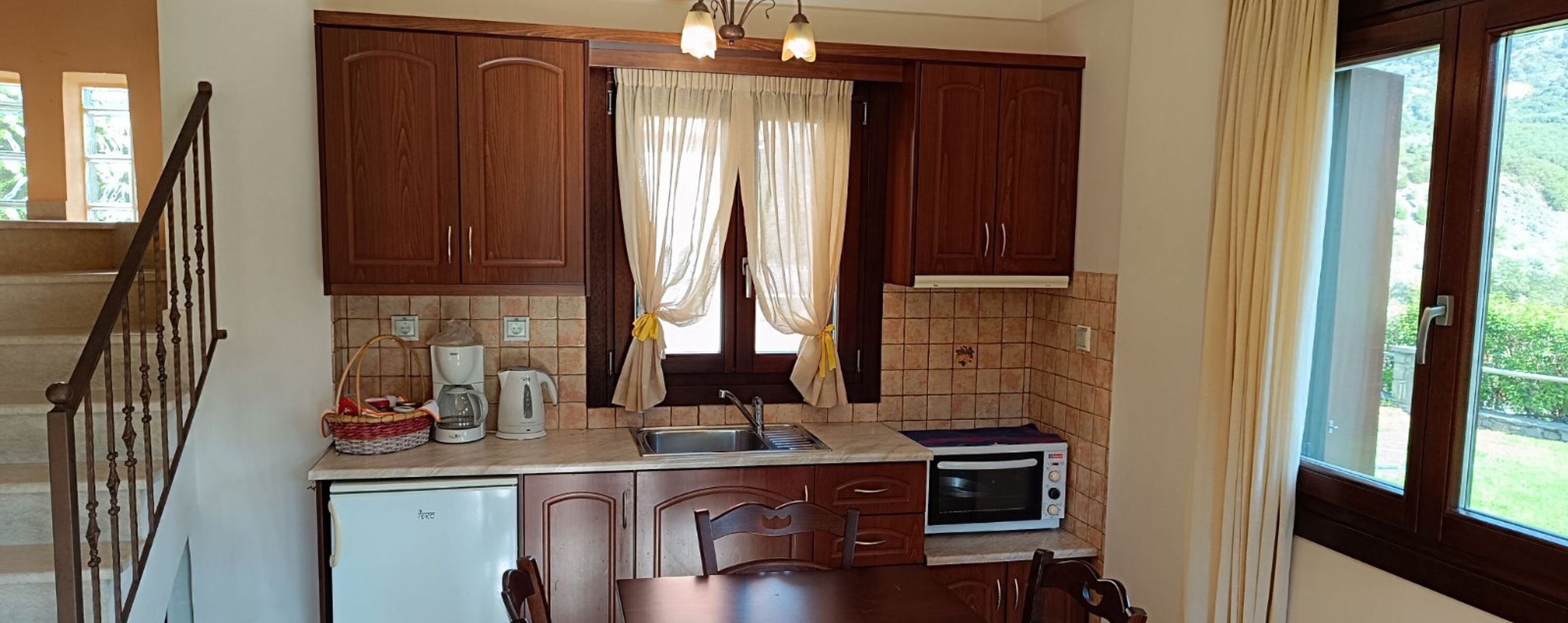 Una cocina compacta con armarios de madera, un lavamanos, un microondas y un comedor.