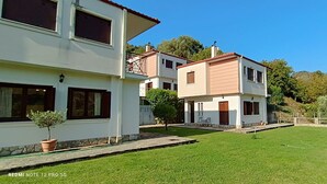 Uma casa de dois andares com um gramado bem cuidado e uma pequena árvore em primeiro plano.