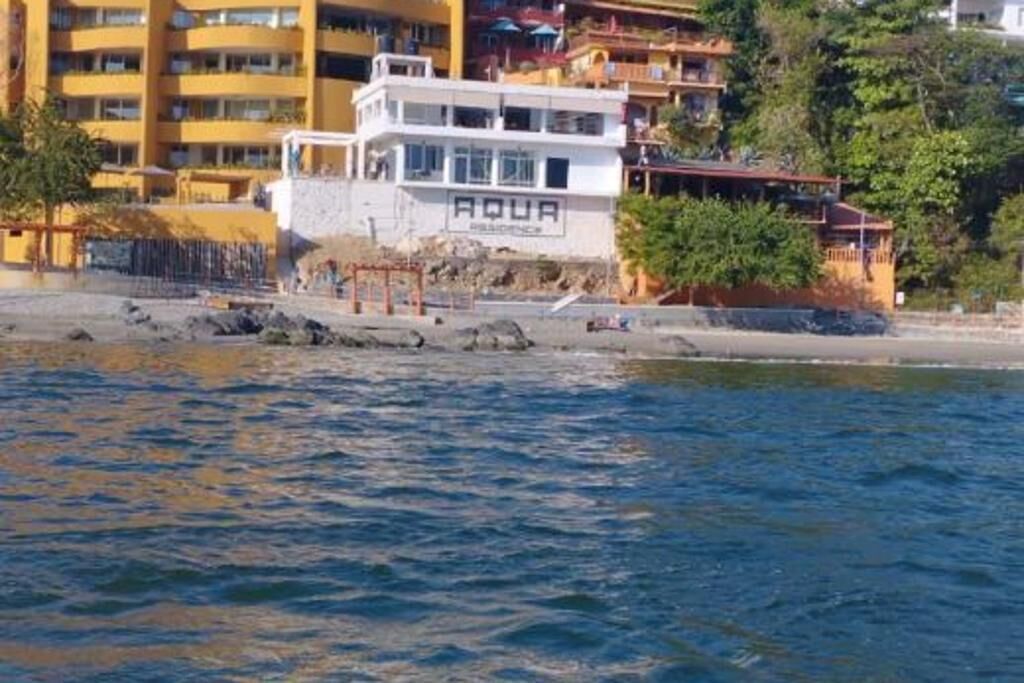 A coastal building with the sign "AQUA" on the side, adjacent to a rocky shoreline.