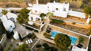 A white villa with a swimming pool, outdoor seating, and a garden. - Baroness in Mykonos with 5 bedrooms and 4.5 bathrooms (Mykonos)
