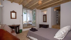 A bedroom with a wooden ceiling, a bed with a white pillow, a small table with a mirror, and a view of an outdoor area. - Baroness in Mykonos with 5 bedrooms and 4.5 bathrooms (Mykonos)
