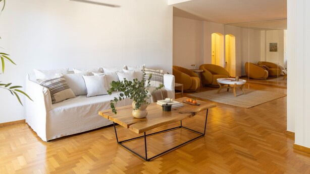 A modern living room with a white sofa, wooden coffee table, and a potted plant. - Acropolis Museum Retreat - 2 Bedroom Apartment (Athina)