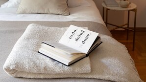 A neatly made bed with a beige blanket and a book titled "Doing Done." - Acropolis Museum Retreat - 2 Bedroom Apartment (Athina)