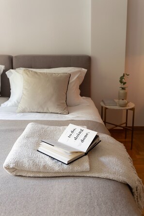 A neatly made bed with a beige blanket and a book titled "Doing Done." - Acropolis Museum Retreat - 2 Bedroom Apartment (Athina)