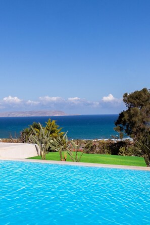 Uma piscina com vista para o mar e montanhas.