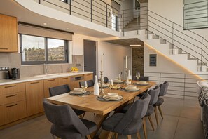 Eine moderne K üche mit Essbereich, mit einem großen Holztisch für sechs Personen, grauen Stühlen und einer Treppe, die zu einer oberen Ebene führt.