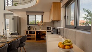 Cozinha moderna com área de jantar, forno embutido e uma grande janela com vista para a cidade.