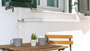 Een houten tafel met twee grijze mokken en een potplant.
