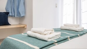 Una cama bien hecha con una manta verde y blanca a rayas y toallas blancas dobladas.