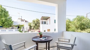 A balcony with a round table, two white chairs, and a potted plant. - Hippocampus - Standard Triple Studio (Moutsouna)