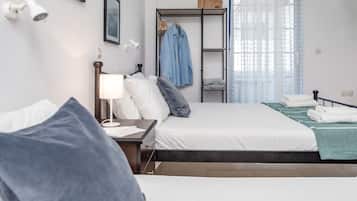 A modern hotel room with a large bed, a bedside table with a lamp, a wardrobe, and a view of the outdoors through sheer curtains.