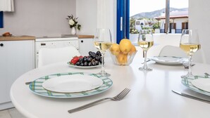 Taula de menjador preparada amb plats, gots i fruita, amb vistes a les muntanyes de fons.