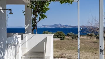 A white building with a staircase leading to a balcony overlooking a coastal view.