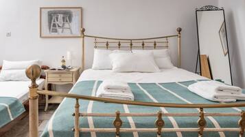 A neatly arranged bedroom with a bed, bedside table, and a mirror.