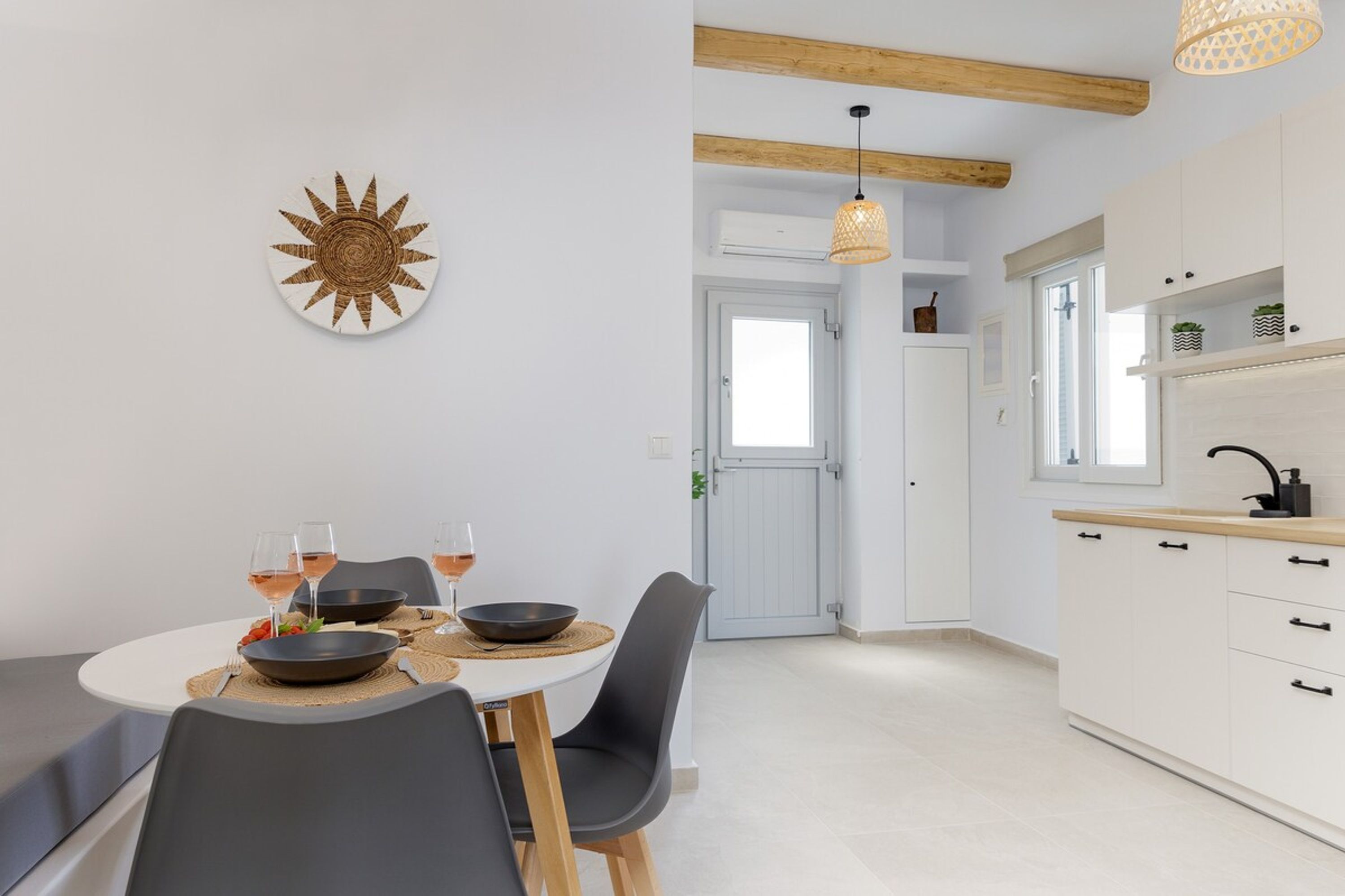 Een moderne keuken met witte kasten, een eettafel met stoelen en een hangende lamp.