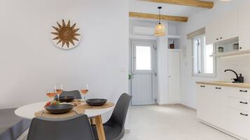 Een moderne keuken met witte kasten, een eettafel met stoelen en een hangende lamp.