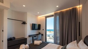 Ein modernes Hotelzimmer mit Bett, Schreibtisch, Fernseher und einem Balkon mit Aussicht.