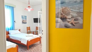 Una stanza con un letto, una scrivania, una sedia, un quadro raffigurante una spiaggia e una finestra con tende.