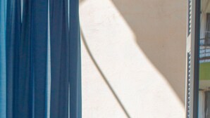 Un balcone con un tavolo, una sedia e una finestra con tende.