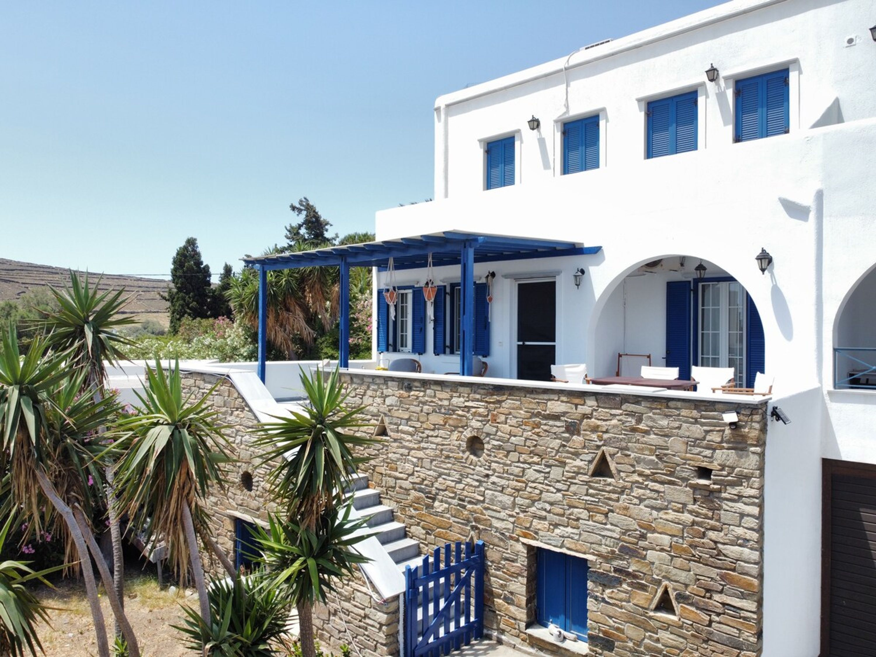 A white building with blue shutters and a stone facade.