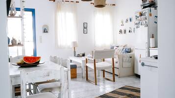 A bright, well-lit kitchen with white cabinetry, a dining table with chairs, and a refrigerator with magnets and pictures.