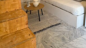 Ein modernes Wohnzimmer mit einer Holztreppe, einem runden Couchtisch, einer Couch und einem wandmontierten Spiegel.