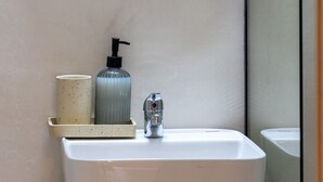 Une salle de bain avec un lavabo blanc, un miroir et un distributeur de savon.