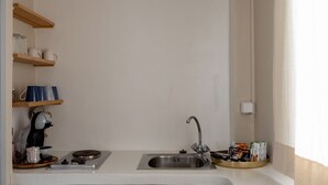 A kitchen with a sink, wooden shelves, and a coffee machine. - Salt & Stone In Center Of Tinos Luxury Suite (Tinos)