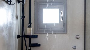A shower with a handheld showerhead, a fixed showerhead, and a window above the shower. - Salt & Stone In Center Of Tinos Luxury Suite (Tinos)