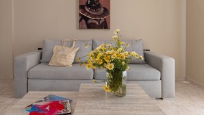 Een woonkamer met een grijze bank, een vaas met gele bloemen en een tijdschrift op de salontafel.