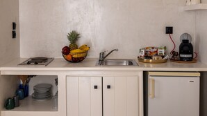 Een keuken met een gootsteen, fornuis en koelkast. Op het aanrecht staat een fruitschaal met bananen en een ananas.