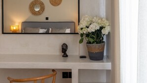 Hotelkamer met een bed, een bedlampje, een spiegel, een decoratief hoofdschulptuur en een potplant met witte bloemen.