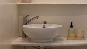 A bathroom with a white sink, a round mirror, and a small Buddha statue. - Atheria In Center Of Tinos With Two Single Beds (Tinos)