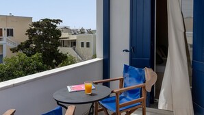 A balcony with a table, chairs, and a glass of orange juice. - Atheria In Center Of Tinos With Two Single Beds (Tinos)