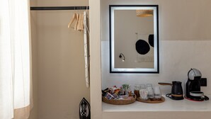 A bathroom with a towel rack, a mirror, a coffee maker, and a basket of toiletries. - Atheria In Center Of Tinos With Two Single Beds (Tinos)