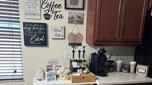 Een keuken met houten kastjes, een koffiehoek en diverse keukenbenodigdheden.