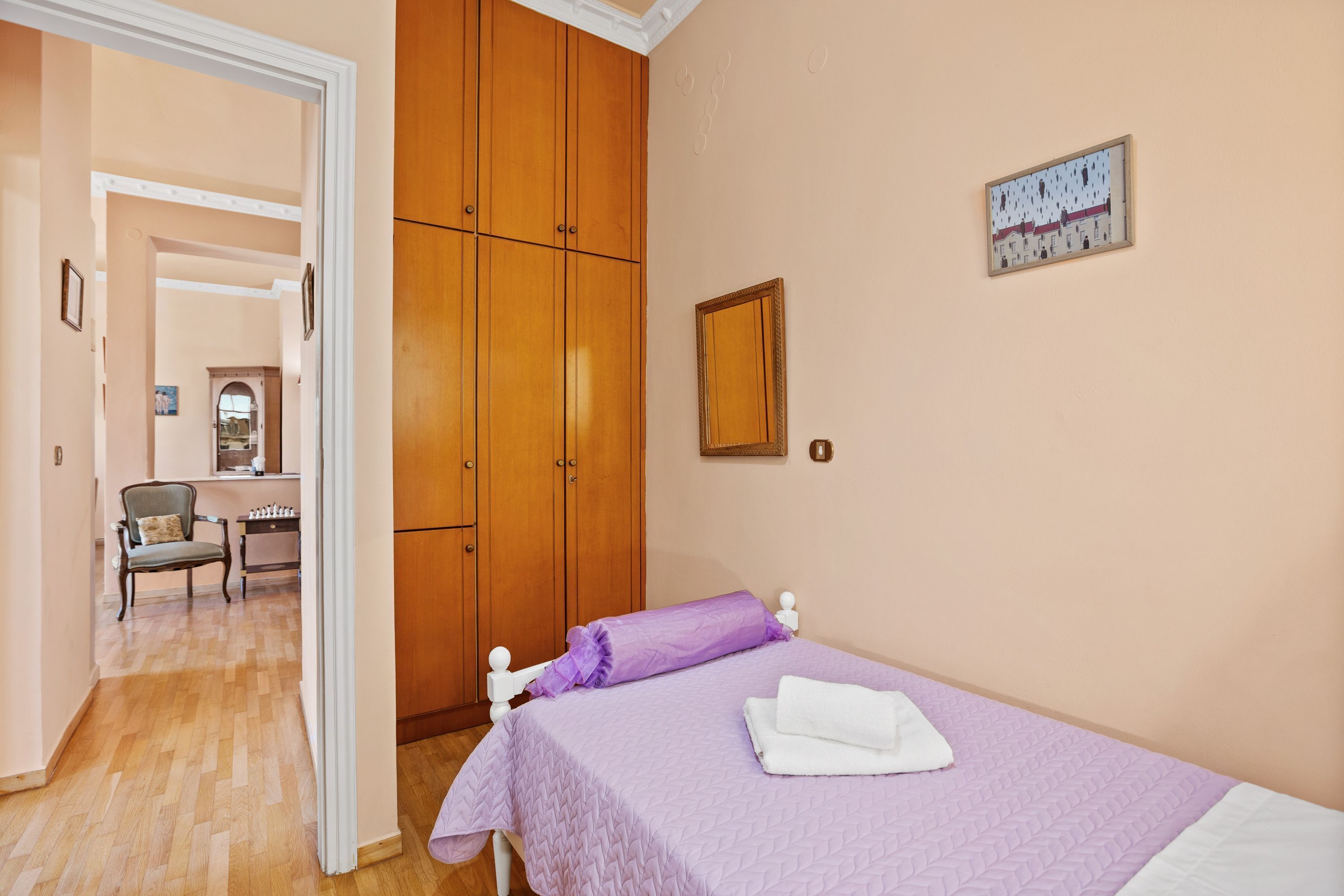 A bedroom with a bed, a wardrobe, a chair, and a desk.