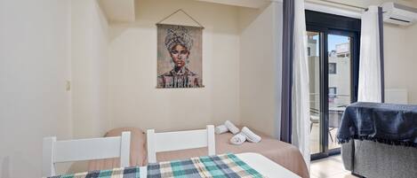 A bedroom with a bed, a painting on the wall, and a view through a glass door.