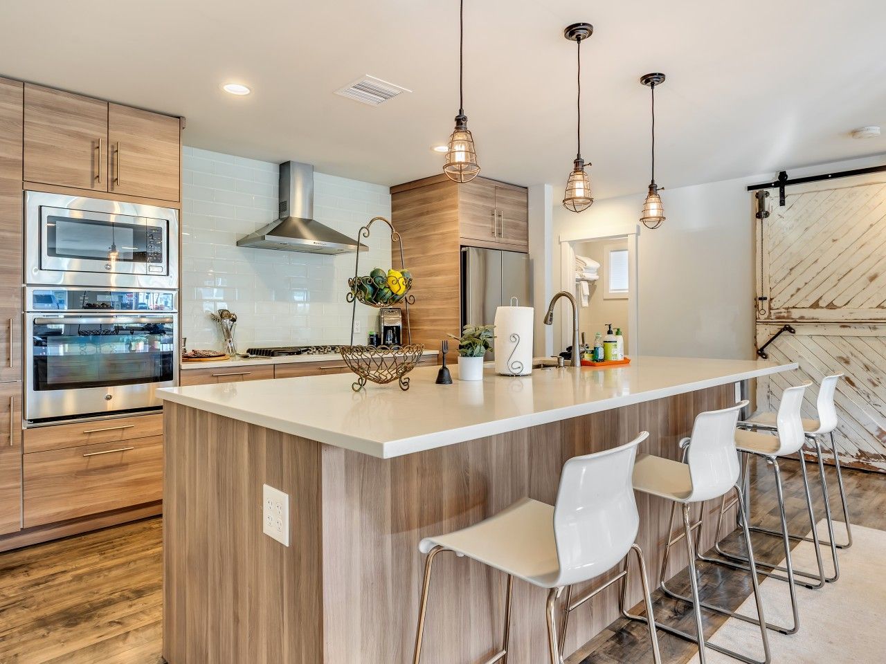 A modern kitchen with a central island, stainless steel appliances, and pendant lighting.